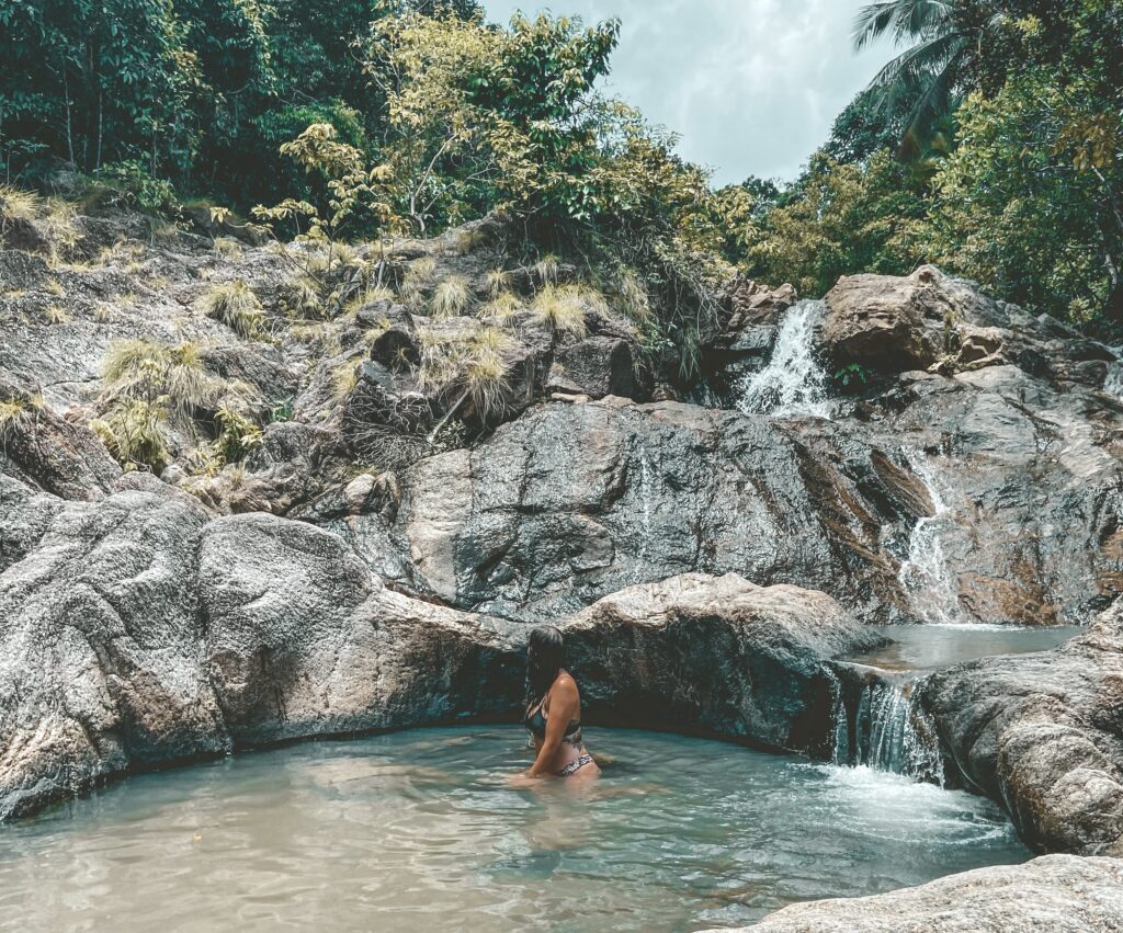 Aly sitting in a waterfall