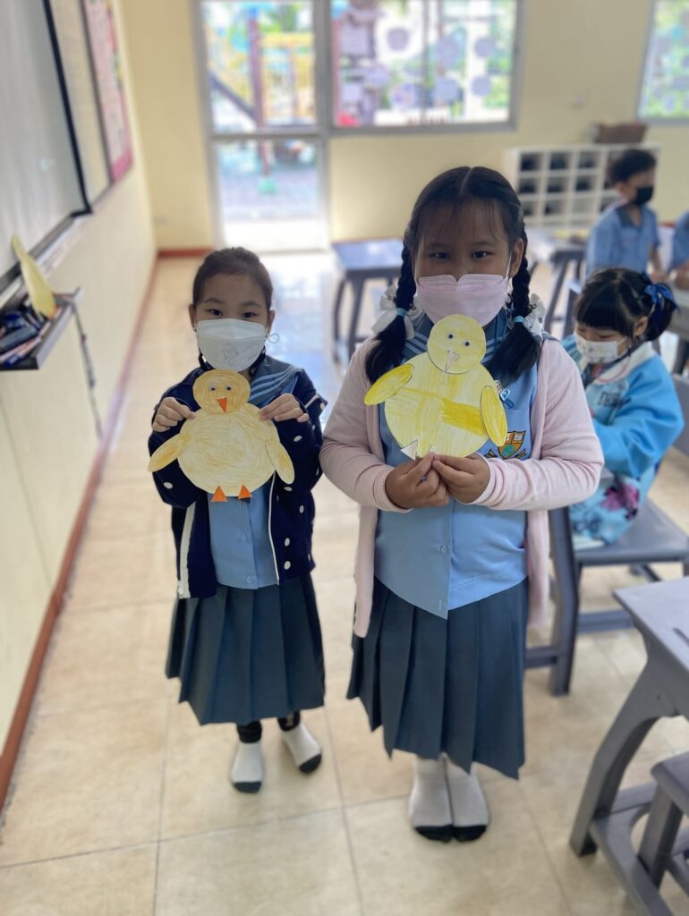 Two young girls holding their chick art projects 